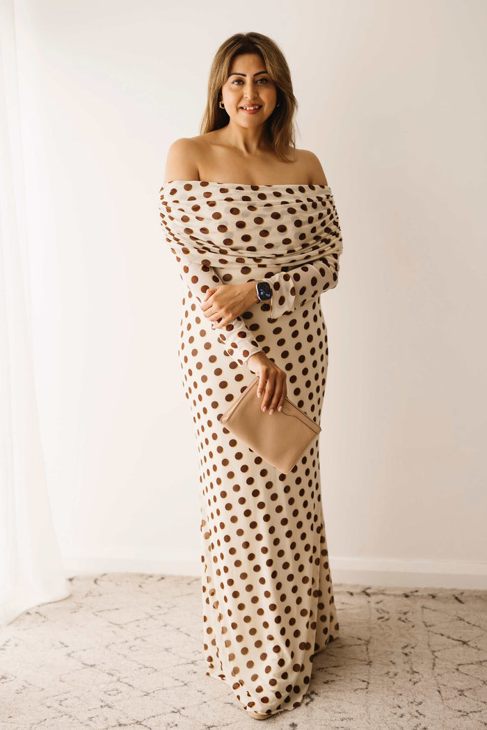 A lady wearing the Mama Rentals AFRM Thelma Off Shoulder Mesh Maxi Dress in Gold in a studio.
