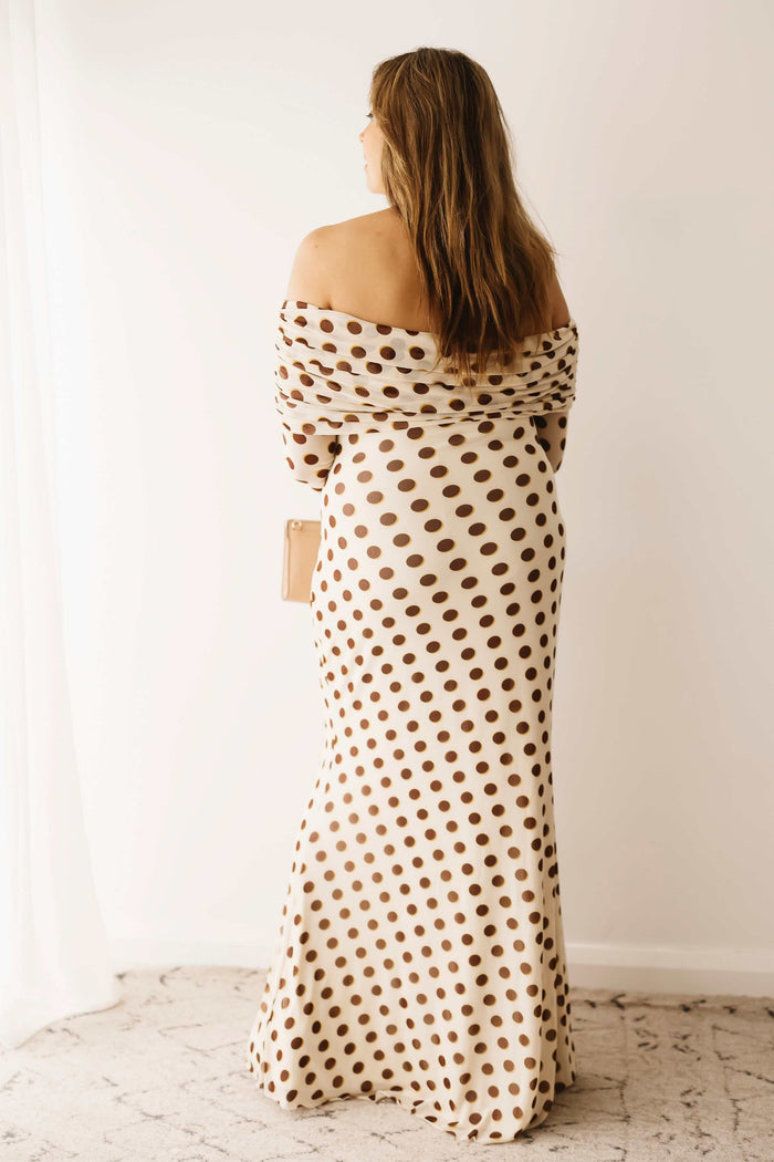 A lady wearing the Mama Rentals AFRM Thelma Off Shoulder Mesh Maxi Dress in Gold in a studio.