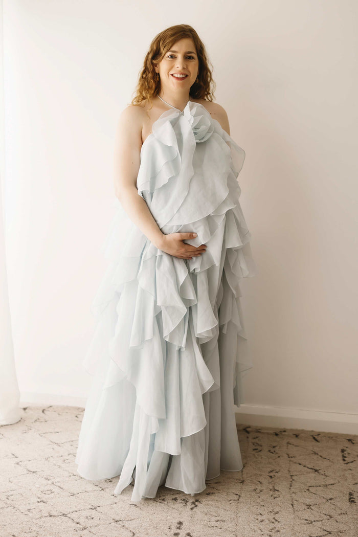 A pregnant lady wearing the Mama Rentals Aje Pandorea Layered Maxi Dress - Silver Blue in a studio.